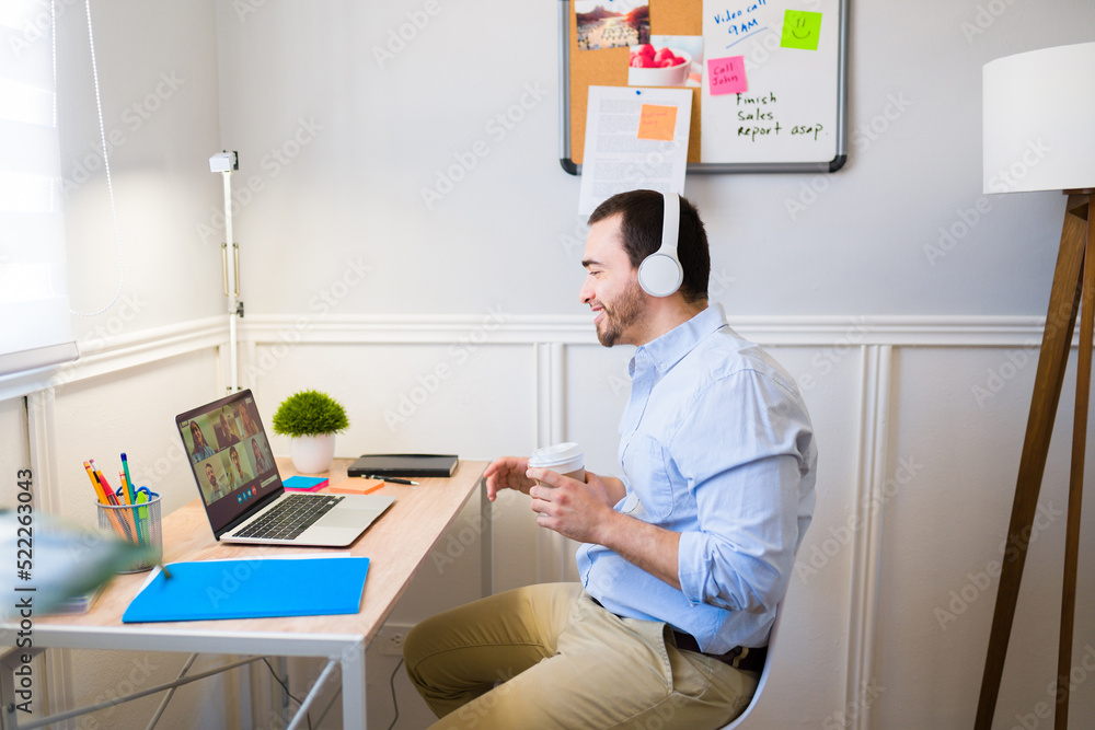 Cheerful man working from home and having a work video call at his desk