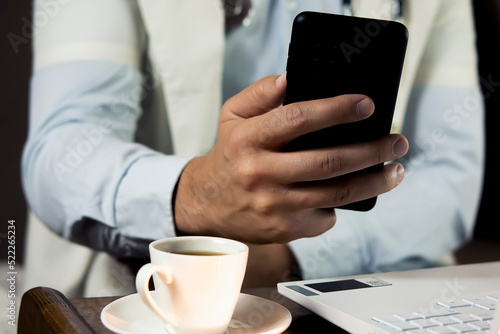 Close-up of doctor using phone at his office, doctor working online, Online consultation. Unrecognizable doctor uses smartphone at workplace, chats with patient, prescribes treatment