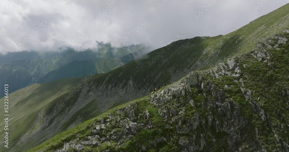 aerial view of walking tourists apperaing from the behind the stones and going down the mountain range aerial view of walking tourists apperaing from the behind the stones and going down the mountain range