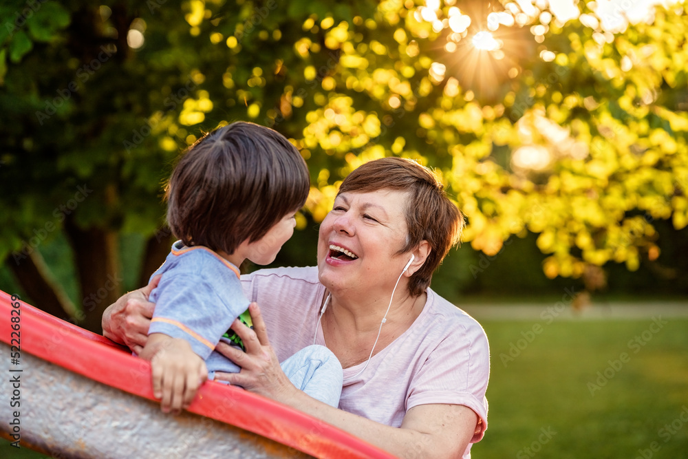 Portrait of happy smiling senior plus size woman having fun with grandson in park outdoors at warm sunny summer day Portrait of happy smiling senior plus size woman having fun with grandson in park outdoors at warm sunny summer day