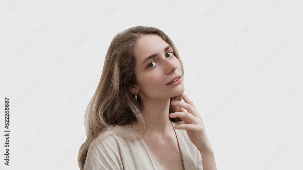 Studio portrait of a beautiful young woman looking at camera and smiling. Isolated on light grey background. Beauty concept Studio portrait of a beautiful young woman looking at camera and smiling. Isolated on light grey background. Beauty concept