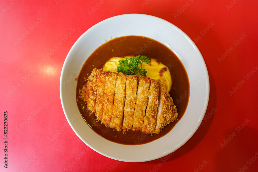japanese food style : Katsu or fried pork Curry Rice with omelet put in the white plate on the table. japanese food style : Katsu or fried pork Curry Rice with omelet put in the white plate on the table.