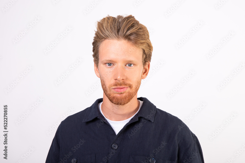 Portrait of young Caucasian man grinning at camera. Bearded man wearing T-shirt and black shirt standing and smiling at camera. Doubt and uncertainty concept Portrait of young Caucasian man grinning at camera. Bearded man wearing T-shirt and black shirt standing and smiling at camera. Doubt and uncertainty concept