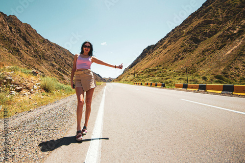 a young single woman of easy virtue, in light sexy clothes, voting on a highway in the desert, traveling alone