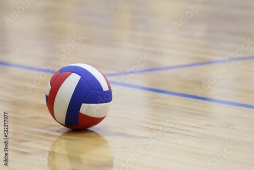 red, white, and blue volleyball on an indoor wood court photo