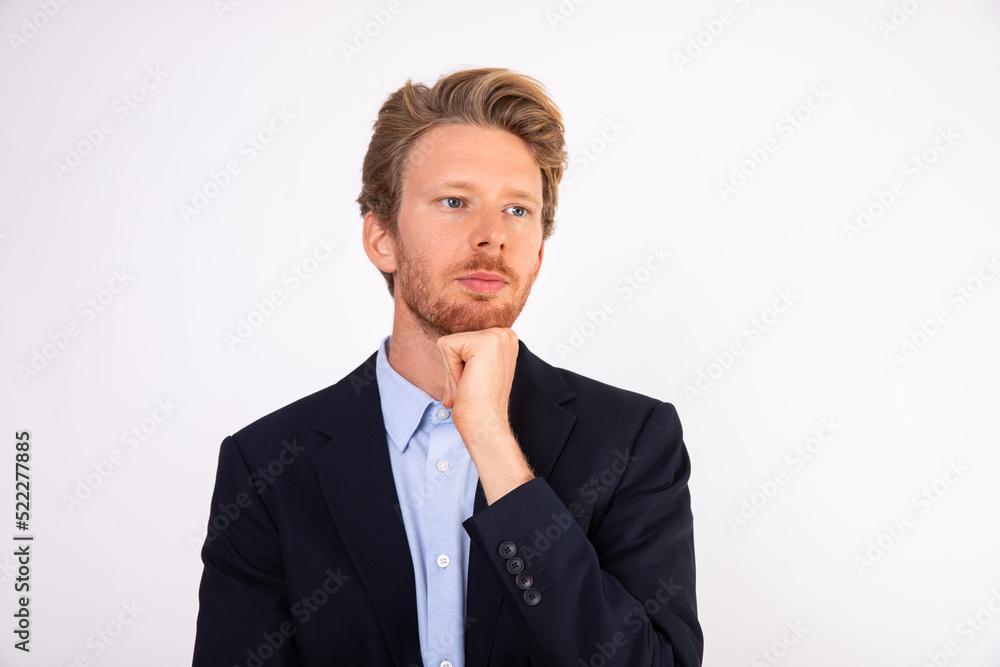Portrait of pensive young Caucasian businessman standing with hand on chin. Manager wearing blue shirt and black suit coat standing and thinking about something. Solving problem concept Portrait of pensive young Caucasian businessman standing with hand on chin. Manager wearing blue shirt and black suit coat standing and thinking about something. Solving problem concept