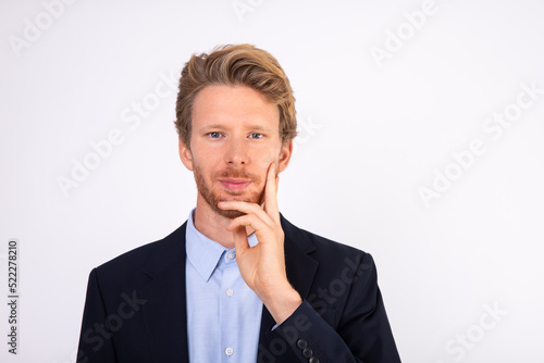 Portrait of young businessman looking at camera with interest. Caucasian manager wearing blue shirt and black suit coat standing and smiling. Interest and curiosity concept