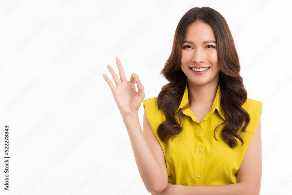 Happy Asian woman wearing a green shirt shows the ok sign and looks at the camera on white background. Happy Asian woman wearing a green shirt shows the ok sign and looks at the camera on white background.