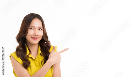 Asian woman with long hair wearing a green shirt is smiling and pointing her finger in the white copy space.