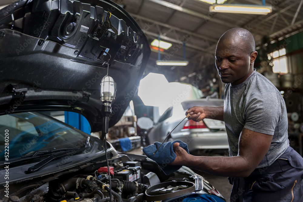 Obraz premium Car mechanic checking oil quality the engine motor car Transmission and Maintenance Gear. car mechanic in an auto repair shop is checking the engine.