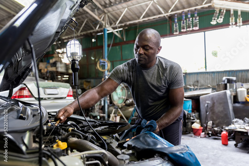 Car mechanic checking oil quality the engine motor car Transmission and Maintenance Gear. car mechanic in an auto repair shop is checking the engine.