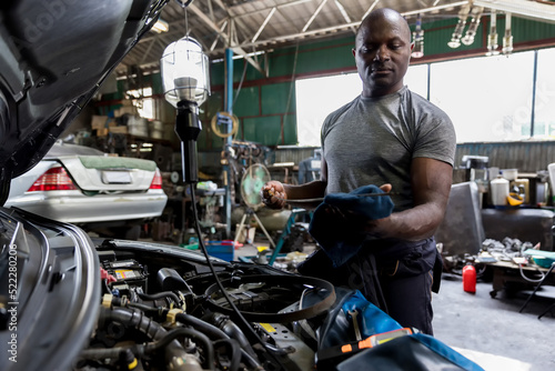 Car mechanic checking oil quality the engine motor car Transmission and Maintenance Gear. car mechanic in an auto repair shop is checking the engine.
