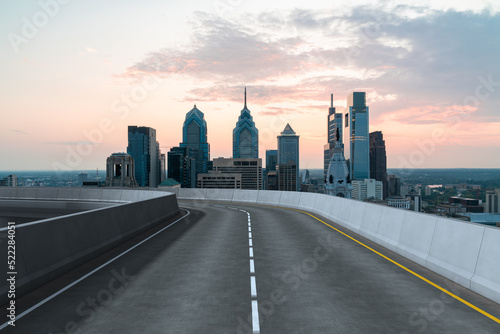 Empty urban asphalt road exterior with city buildings background. New modern highway concrete construction. Concept way to success. Transportation logistic industry fast delivery. Philadelphia. USA.