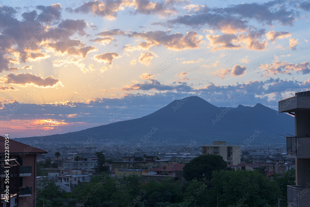 Angri, Italy. View of the south-east side of Mount Vesuvius at sunset with the town of Angri and its residential buildings in the foreground. June 04, 2020.