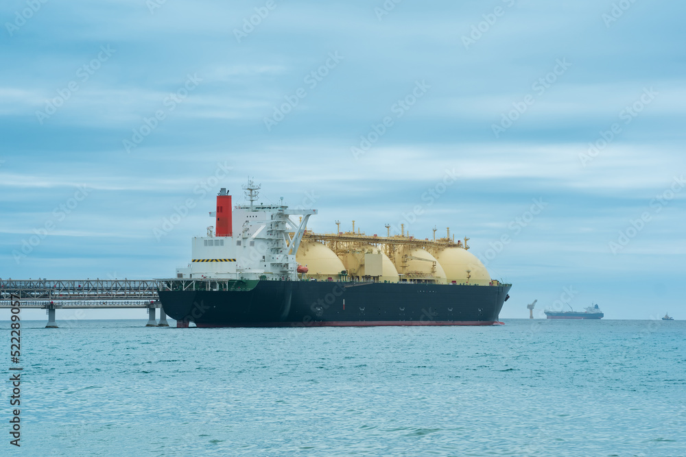 liquefied natural gas carrier tanker during loading at an LNG offshore terminal, in the distance the oil export terminal is visible in the sea
