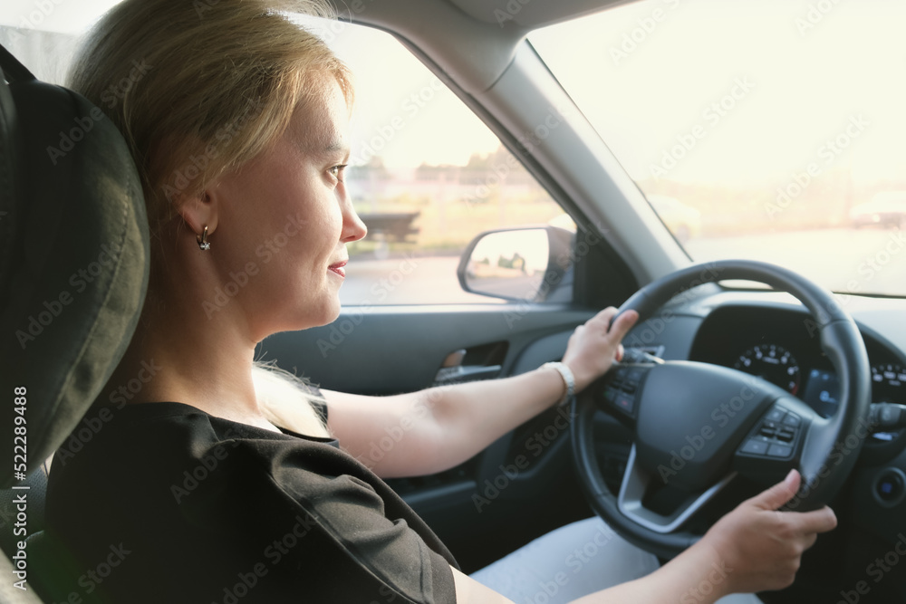 Young attractive woman drives a car. Profile photo of a beautiful blonde woman with long hair. Woman in a car while driving. Young attractive woman drives a car. Profile photo of a beautiful blonde woman with long hair. Woman in a car while driving.