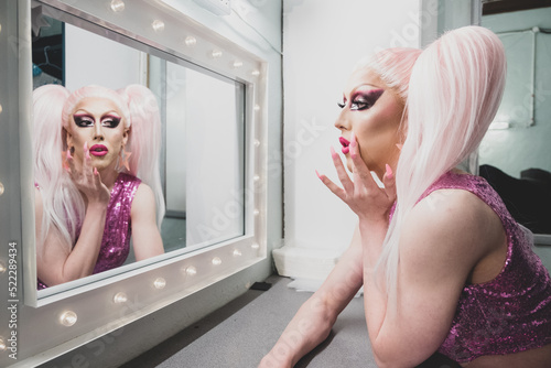 Fotografie Drag Queen applying Make-up Backstage and looking in Mirror before Performance