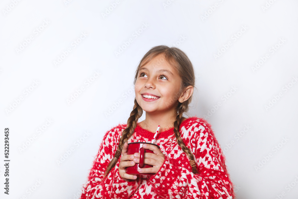 Smiling little girl in warm sweater holding a cup with a warm drink on white background Smiling little girl in warm sweater holding a cup with a warm drink on white background