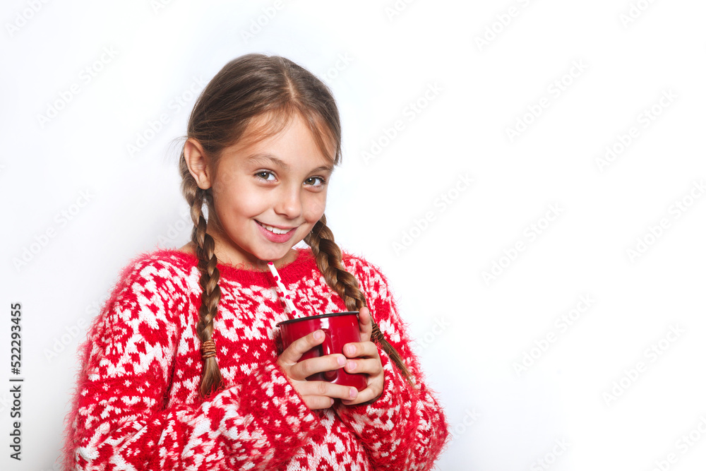 Smiling little girl in warm sweater holding a cup with a warm drink on white background Smiling little girl in warm sweater holding a cup with a warm drink on white background