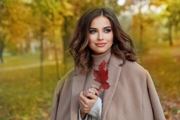 Portrait of cheerful happy woman in fall park outdoor on sunny autumn background