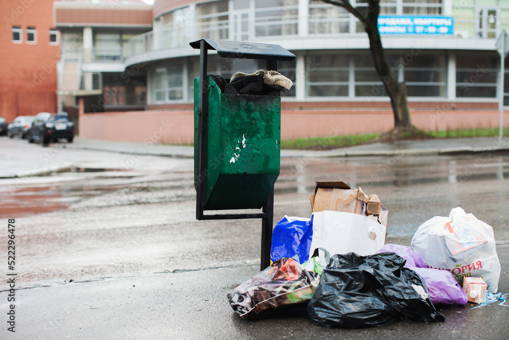 Overflowing garbage container on a city street. Garbage removal problem, ecology concept. Overflowing garbage container on a city street. Garbage removal problem, ecology concept.
