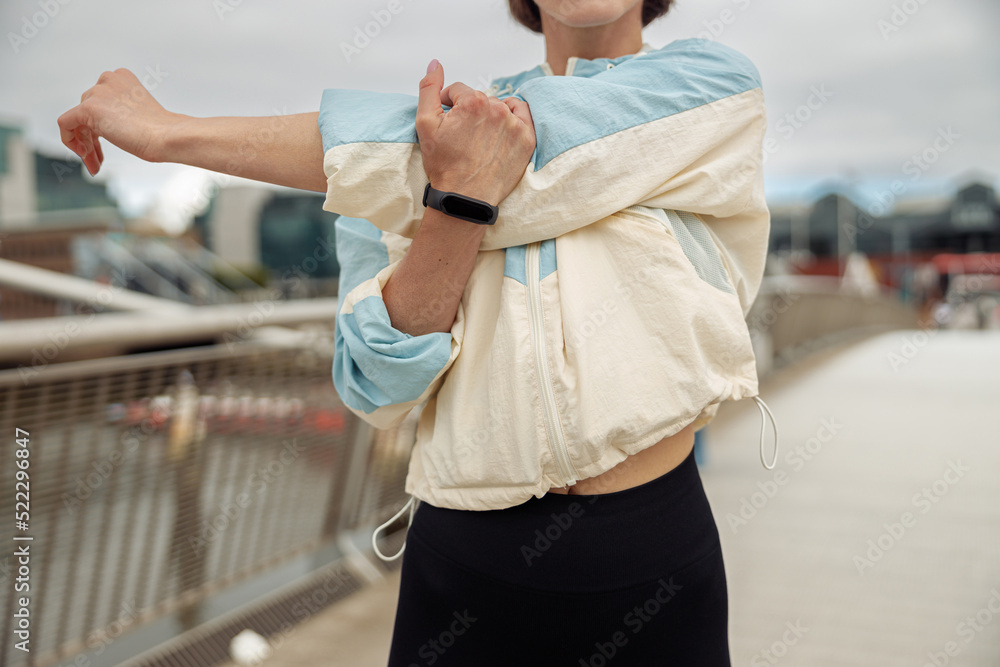 Close up of sportive woman doing stretching exercise on footbridge in the city 