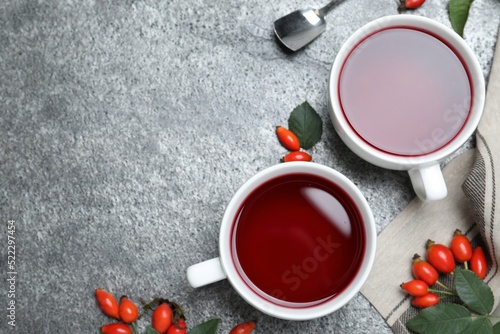 Fresh rose hip tea and berries on grey table, flat lay. Space for text