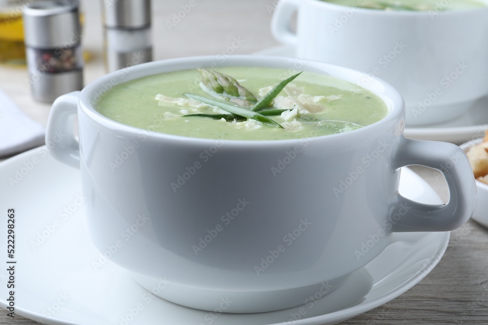 Delicious asparagus soup with green onion on white table, closeup Delicious asparagus soup with green onion on white table, closeup