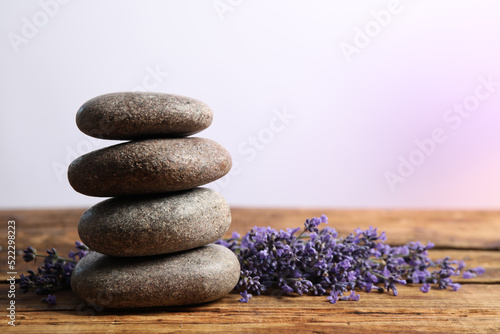 Lavender flowers and spa stones on wooden table. Space for text