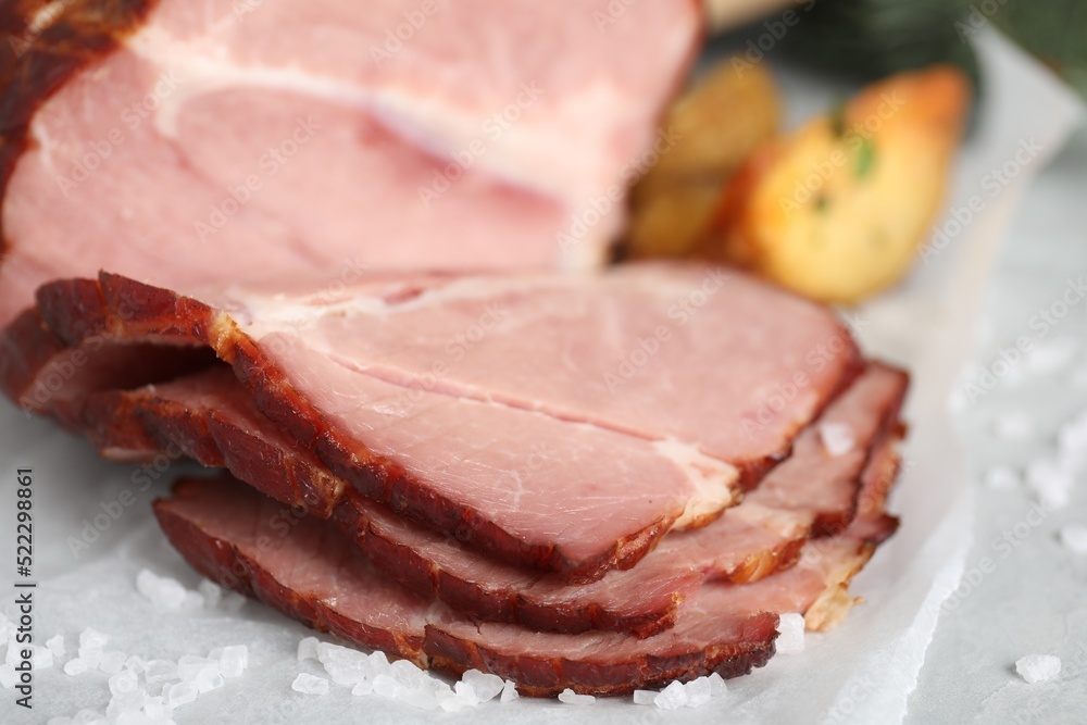Cut delicious ham with salt on table, closeup