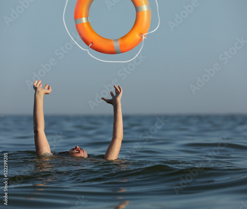 Drowning woman with raised hands getting lifebelt in sea