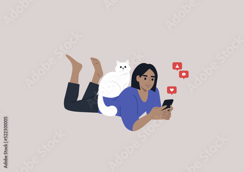 A young female Caucasian character lying on their stomach and checking their mobile phone notifications, a cat sitting on their back