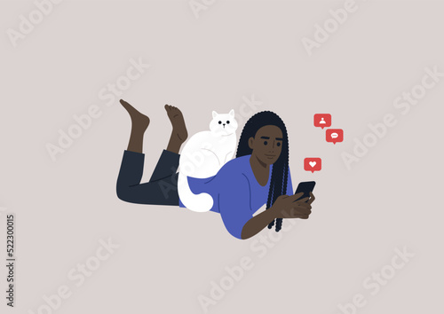 A young female African character lying on their stomach and checking their mobile phone notifications, a cat sitting on their back