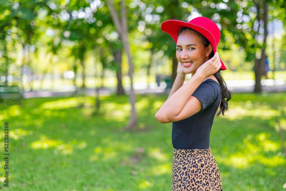 Portrait photo of the beautiful moment of a young asian beautiful lady with red hat happily posing and relax in a garden park strolling