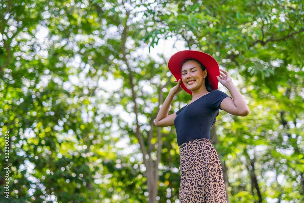Portrait photo of the beautiful moment of a young asian beautiful lady with red hat happily posing and relax in a garden park strolling