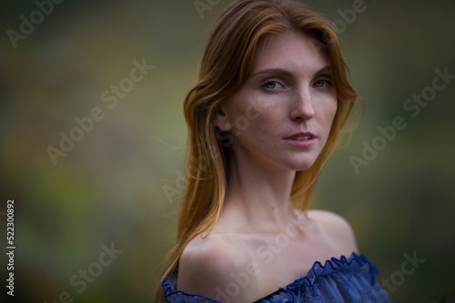 A beautiful red-haired girl in a blue dress walks in the mountains. Portrait.