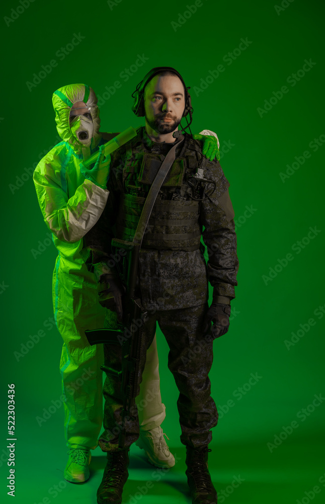 soldier in studio on green background with medic or scientist a man in military uniform with a rifle or machine gun of a man in chemical protection put a syringe to his neck. chemical bacterial threat soldier in studio on green background with medic or scientist a man in military uniform with a rifle or machine gun of a man in chemical protection put a syringe to his neck. chemical bacterial threat