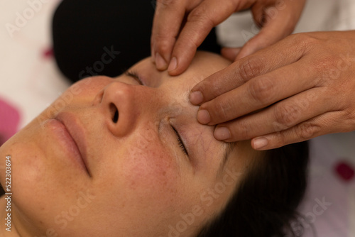 Latina woman receiving a Shiroadhyanga massage on the face with specific pressure points