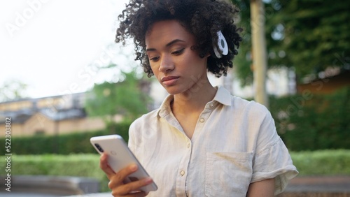 Beautiful woman listening to music in headphones, using app on smartphone