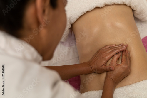 Latina woman receiving a body slimming massage with specific pressure points