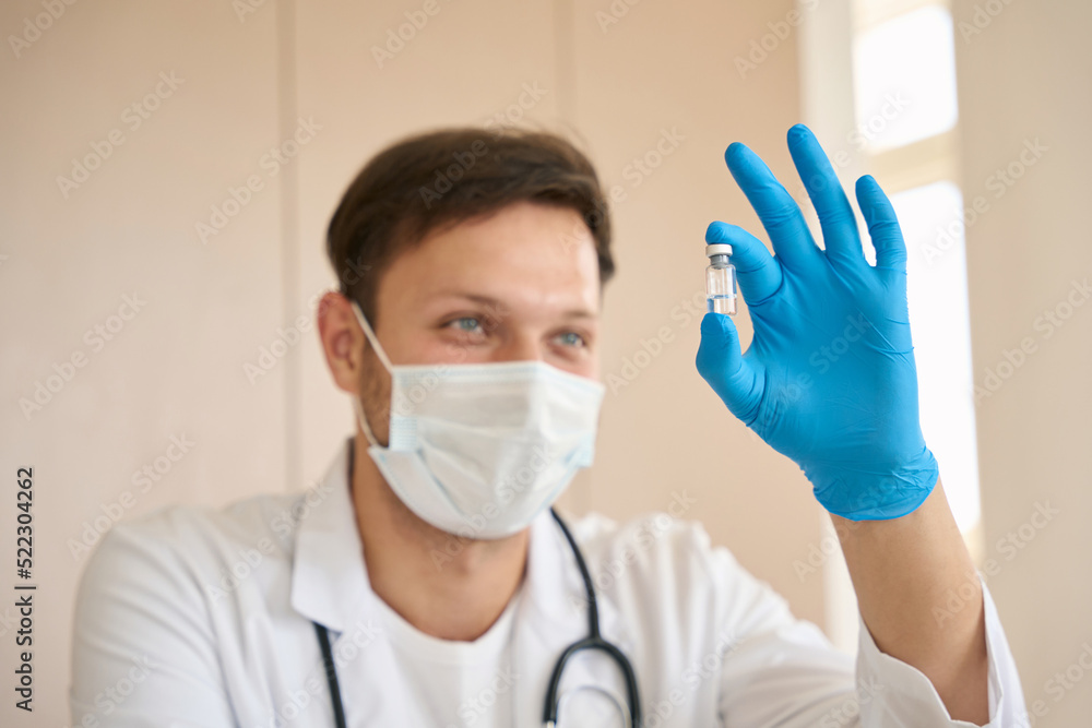 Doctor holds a vial of vaccine in his hands Doctor holds a vial of vaccine in his hands
