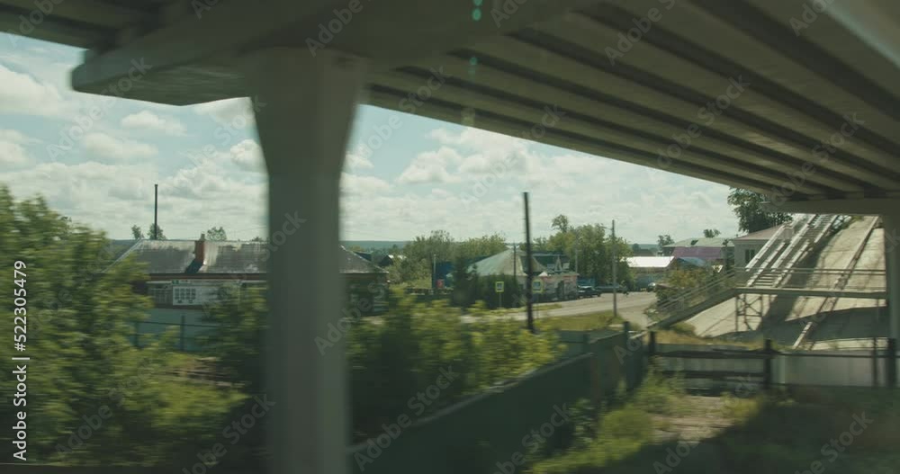 View from the window of a moving train. Rural landscape with private houses. View from the window of a moving train. Rural landscape with private houses.