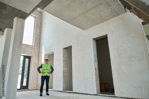 Serious male foreman inspecting a huge unfinished house