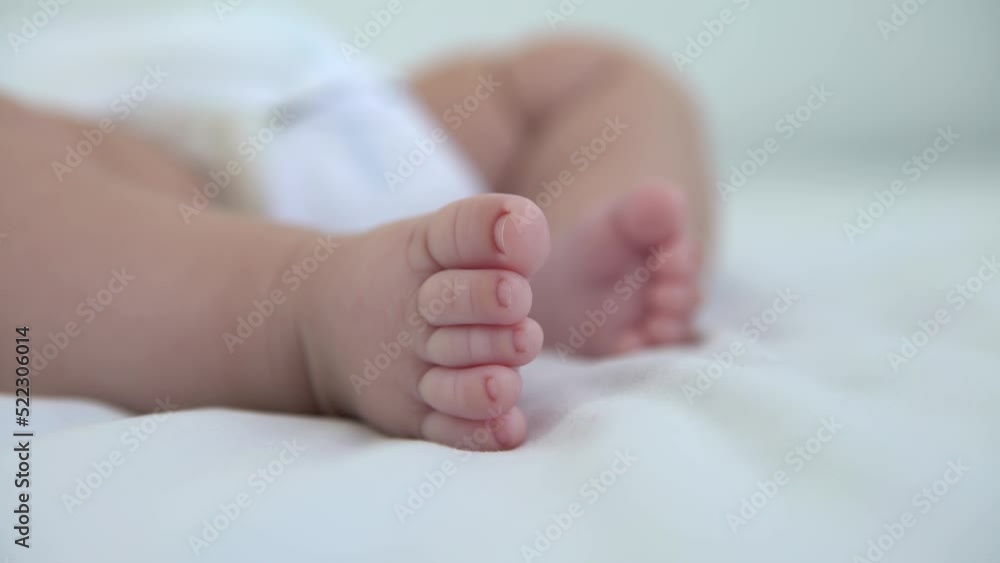 A foots of the newborn on a white sheet background. Tiny foot of a baby boy. Family and home concept with copy space. A foots of the newborn on a white sheet background. Tiny foot of a baby boy. Family and home concept with copy space.