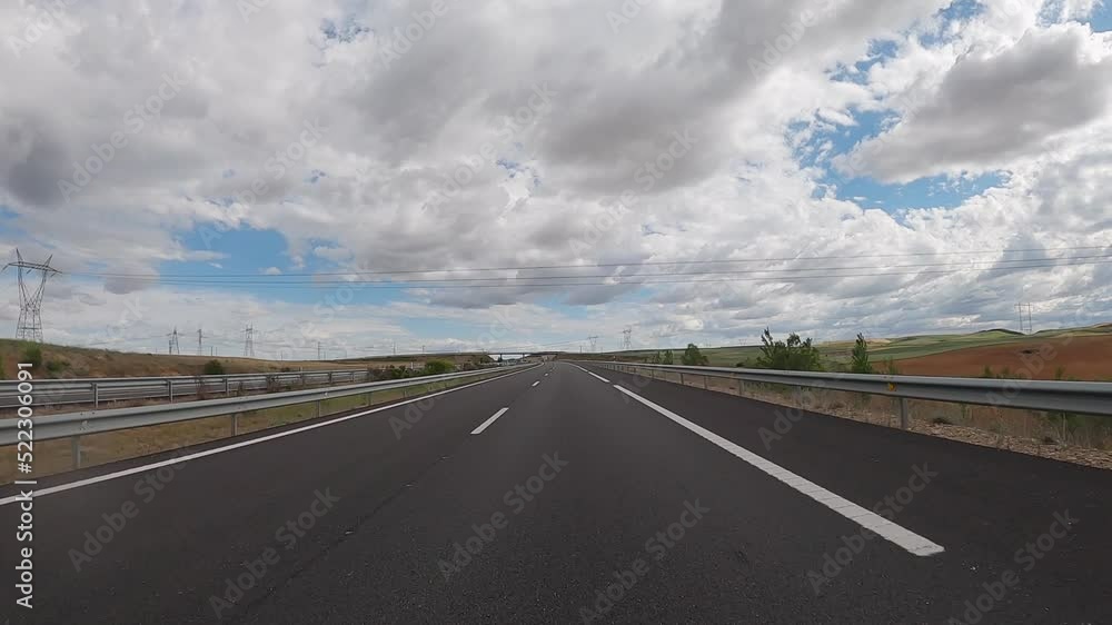 POV driving a car on empty highway road through the fields outside the city during sunny day. Two way asphalt road country views with low clouds at Spain. Traffic ways transportation concept. POV driving a car on empty highway road through the fields outside the city during sunny day. Two way asphalt road country views with low clouds at Spain. Traffic ways transportation concept.