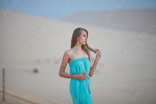Beautiful young woman meeting dawn in the desert. The start of a new day. Freshness of the morning. Long light hair.
