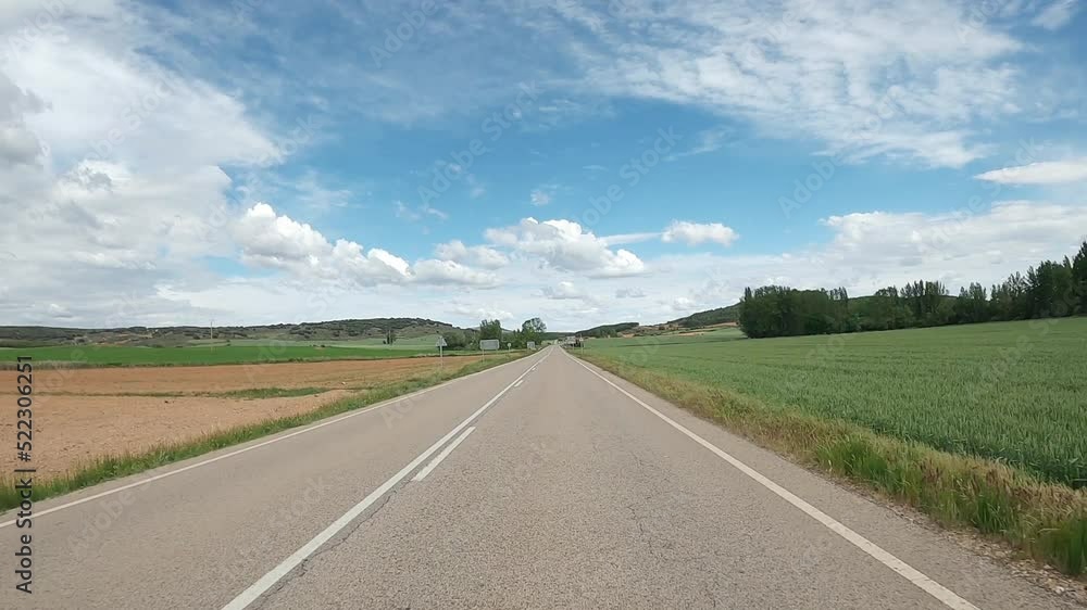 Driving car on empty regional road through the fields outside the city during sunny day in Spain. Countryside asphalt road landscape scene. Traffic ways transportation logistics and traveling concept Driving car on empty regional road through the fields outside the city during sunny day in Spain. Countryside asphalt road landscape scene. Traffic ways transportation logistics and traveling concept
