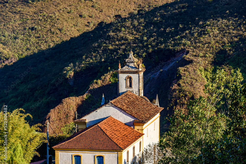 Historic baroque church in Ouro Preto city with hill in the background during the late afternoon