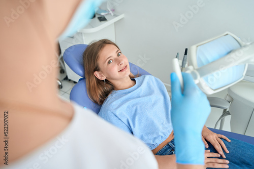 Adolescent girl listening to pediatric dentist during consultation