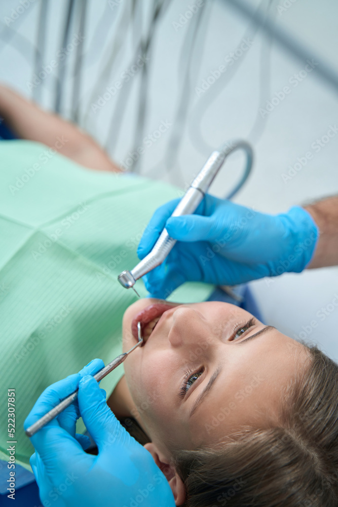 Experienced doctor treating caries in young patient Experienced doctor treating caries in young patient